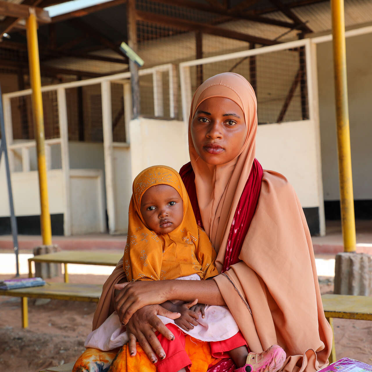 Damac sits with her daughter, Nimo, who is receiving EU-funded treatment for malnutrition, as they wait for a routine nutrition check-up in Health Post L, in  Hagadera, Kenya. 